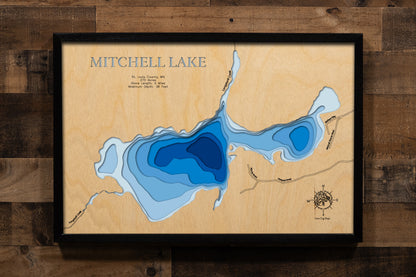 A precision laser-cut, multi-layered wooden map of Mitchell Lake in St. Louis County, Minnesota — a pristine wilderness lake near the edge of the Boundary Waters. The natural wood top layer captures 5 miles of remote, forested shoreline in fine detail, while a light-to-dark blue gradient conveys the lake's 38-foot depth. A handcrafted statement piece for any northwoods cabin or BWCA lover's wall.