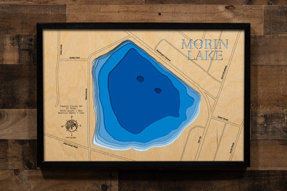 A precision laser-cut, multi-layered wooden map of Morin Lake in Freeborn County, Minnesota, a small 21-acre community lake near Alden in southern Minnesota's agricultural lake country. The natural wood top layer captures its intimate 1-mile shoreline in fine detail, while a light-to-dark blue gradient conveys the lake's shallow, warmwater character. A handcrafted statement piece for any Minnesota lake home or outdoor enthusiast's wall.