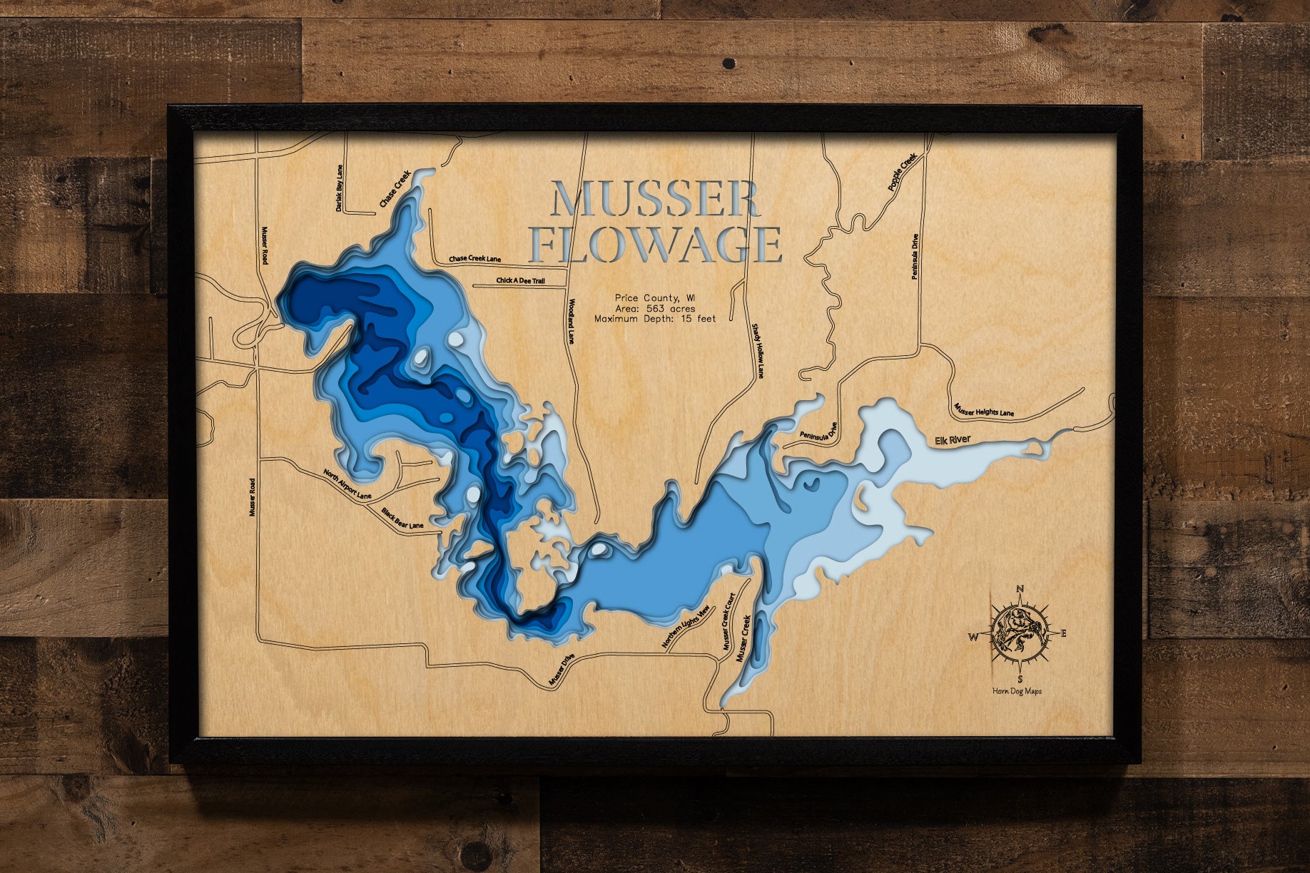 A laser-cut, layered wood map of Musser Lake near Phillips, Wisconsin, showing its irregular shoreline and forested Northwoods surroundings in Price County.