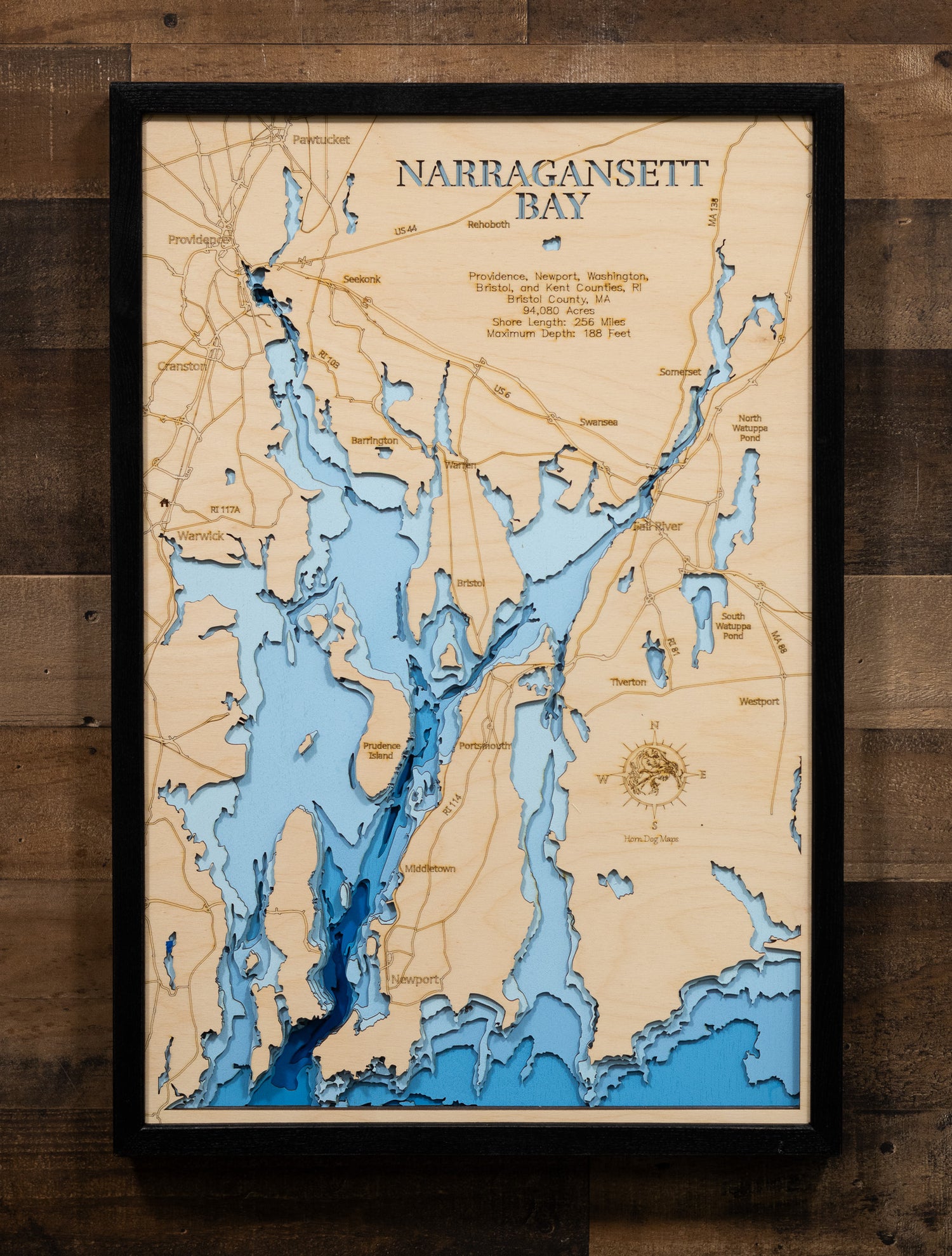 An expertly crafted laser-cut wooden map of Narragansett Bay, New England's largest estuary, showcasing the 147-square-mile bay spanning Rhode Island and Massachusetts, over 30 islands including Aquidneck, Conanicut, and Prudence, 256 miles of intricate shoreline, three distinct passages (West, East, and Sakonnet River), and layered depth contours revealing the 188-foot maximum depth.