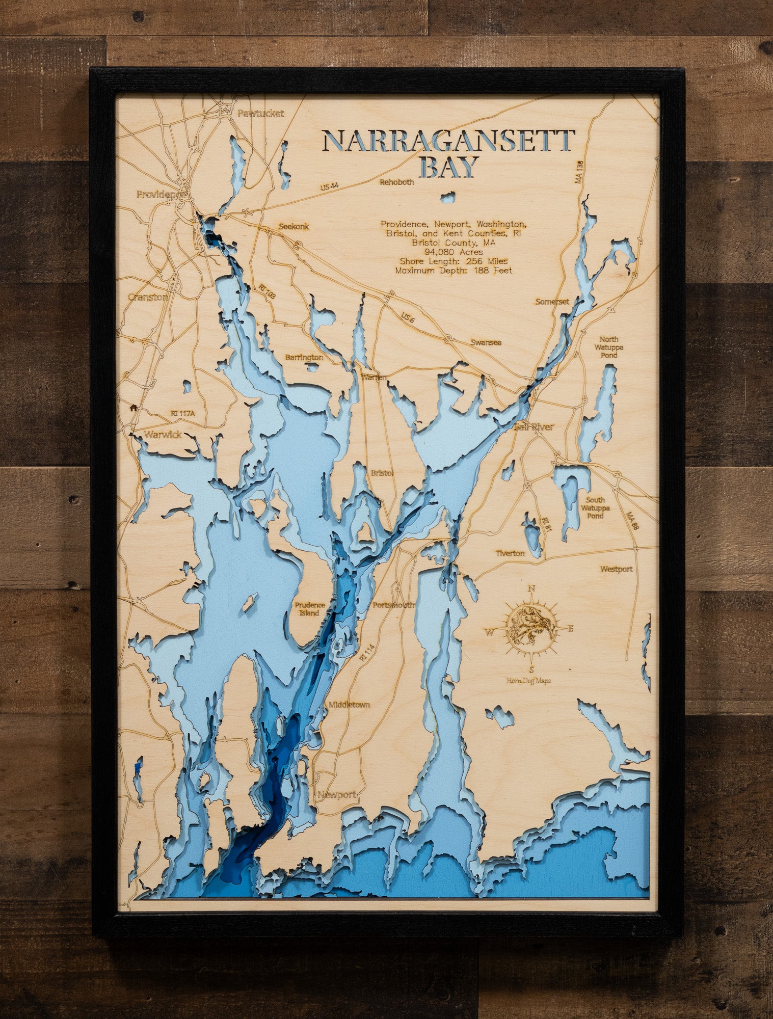 An expertly crafted laser-cut wooden map of Narragansett Bay, New England's largest estuary, showcasing the 147-square-mile bay spanning Rhode Island and Massachusetts, over 30 islands including Aquidneck, Conanicut, and Prudence, 256 miles of intricate shoreline, three distinct passages (West, East, and Sakonnet River), and layered depth contours revealing the 188-foot maximum depth.