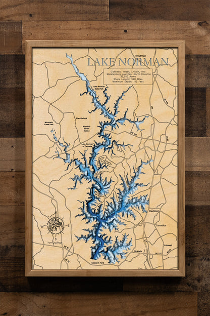 A laser-cut, layered wooden map of Lake Norman in North Carolina. The expansive and highly irregular shape of this large reservoir, with its numerous arms and 520-mile shoreline, is clearly visible as it winds through Iredell, Lincoln, Catawba, and Mecklenburg Counties. The varying depths of the lake, reaching a maximum of 110 feet, are represented by different layers of wood, illustrating its impressive underwater topography.
