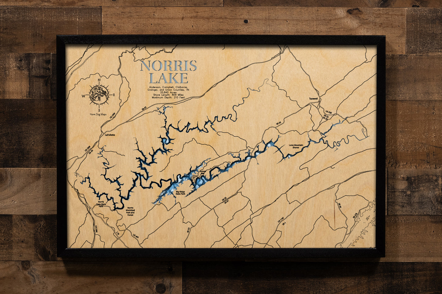 An intricately laser-cut, multi-layered wooden bathymetric map of Norris Lake spanning five Tennessee counties. The detailed three-dimensional relief showcases the 33,840-acre reservoir's impressive 809 miles of winding shoreline through Appalachian valleys, depth contours plunging to the remarkable 210-foot maximum depth near Norris Dam, the convergence of the 73-mile Clinch River and 56-mile Powell River arms, and over 50 islands.