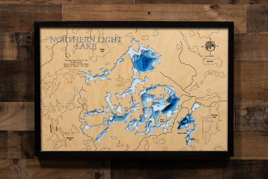 A precision laser-cut, multi-layered wooden map of Northern Light Lake in Thunder Bay District, Ontario, a 16,282-acre Canadian Shield wilderness lake near Atikokan with nearly 218 miles of dramatic shoreline and a maximum depth of 130 feet. The natural wood top layer captures every bay, island, and granite point in fine detail, while a light-to-dark blue gradient conveys the lake's remarkable depth. A handcrafted statement piece for any Ontario fishing camp, wilderness cabin, or Thunder Bay area enthusiast