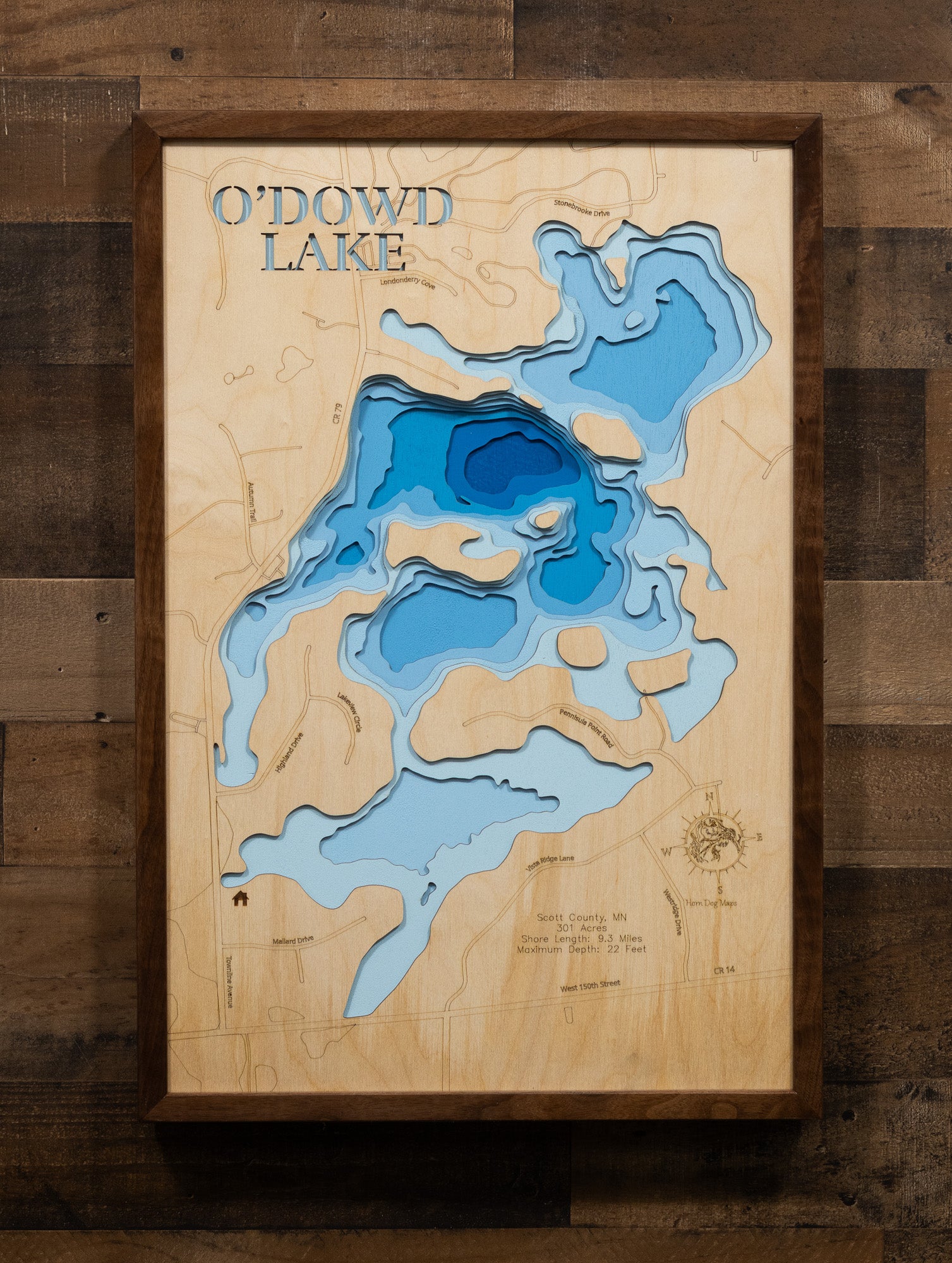 Laser-cut wooden map of O'Dowd in Scott County, Minnesota, showcasing intricate bathymetric contours and depth features etched into premium wood. The 301-acre lake's unique shape and 22-foot maximum depth are beautifully rendered, displaying the underwater structure and terrain that attract anglers to this accessible Twin Cities metro area fishing destination.