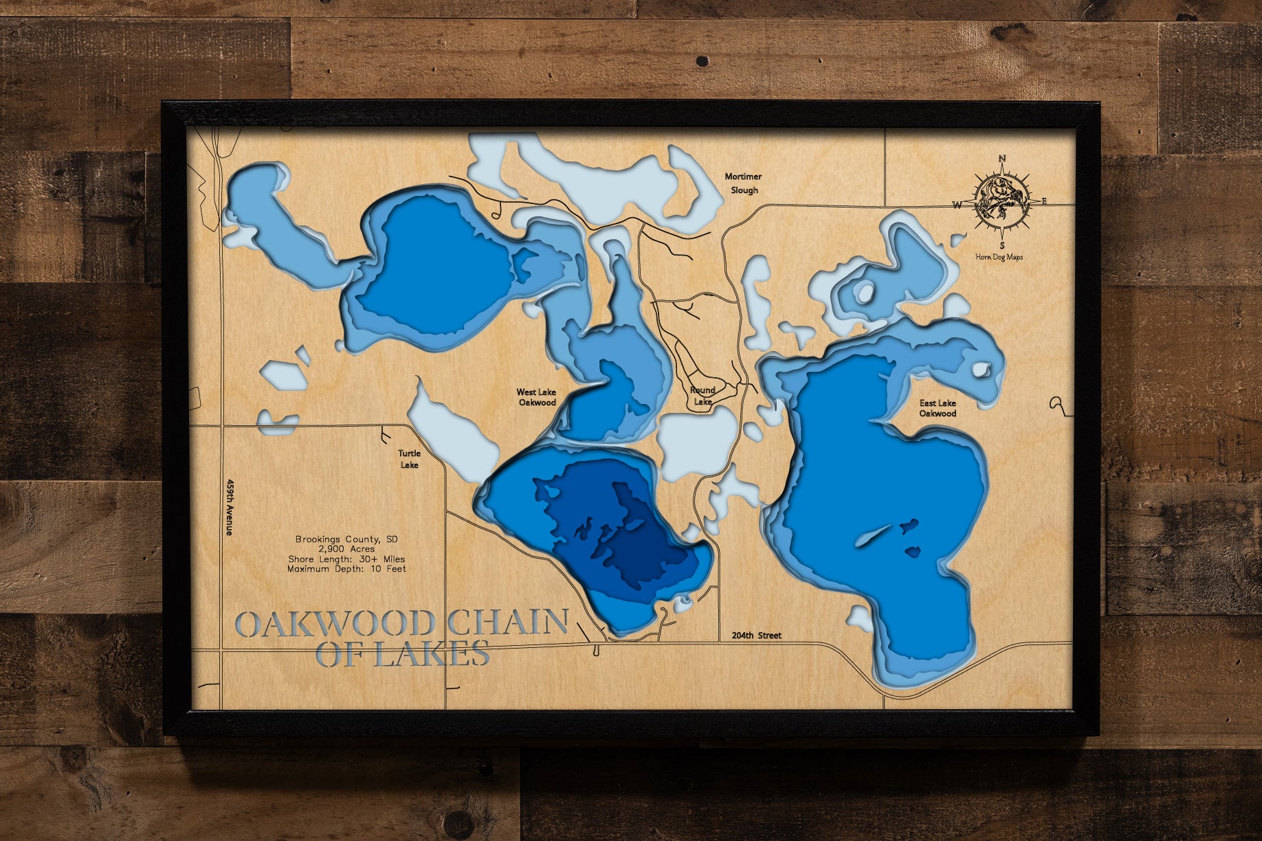 A magnificently detailed, laser-cut, multi-layered wooden topographical map of the Oakwood Lakes chain in Brookings County, South Dakota, showcasing eight connecting glacial lakes spanning nearly 3,000 acres with over 30 miles of intricate shoreline. The natural wood top layer frames the entire interconnected system including Johnson, Tetonkaha, East Oakwood, West Oakwood, and four additional lakes, while graduated blue layers create a gentle visual gradient across the shallow 6-to-10-foot depths.