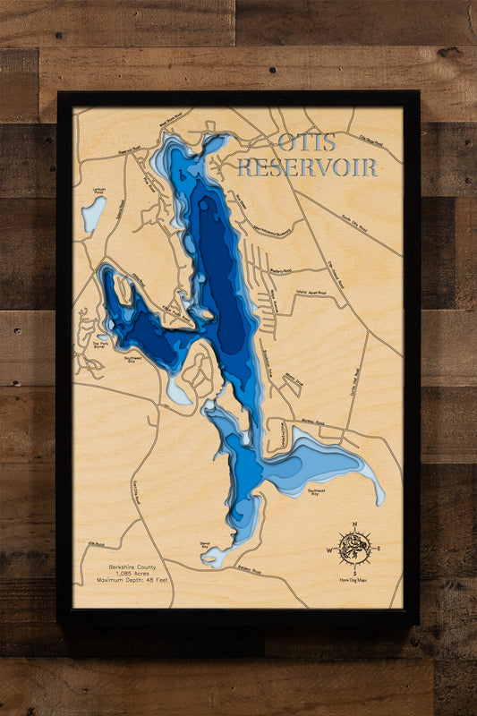 A laser-cut, layered wooden map of Otis Reservoir in Berkshire County, Massachusetts. The shape of this large reservoir, nestled within the rolling Berkshire Hills, is clearly visible within the western Massachusetts landscape. The varying depths of the lake, reaching a maximum of 48 feet, are represented by different layers of wood, illustrating its underwater topography.