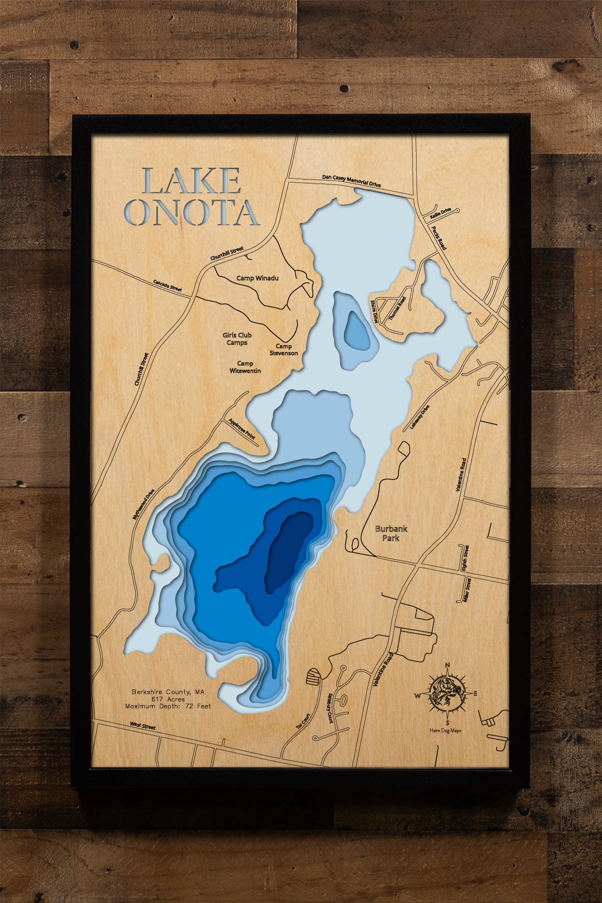 A precision laser-cut, multi-layered wooden map of Lake Onota in Berkshire County, Massachusetts — a 617-acre great pond in Pittsfield with two distinct basins and a maximum depth of 72 feet. The natural wood top layer captures the lake's varied shoreline in fine detail, while a light-to-dark blue gradient conveys its striking depth. A handcrafted statement piece for any Berkshires home, New England cabin, or outdoor enthusiast's wall.