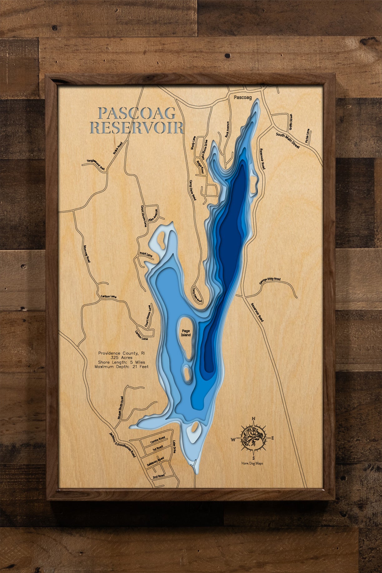 A meticulously crafted, multi-layered laser-cut wooden map of Pascoag Reservoir in Providence County, Rhode Island, showcasing the reservoir's distinctive elongated shape spanning over two miles with five miles of intricate shoreline detail. The depth contours illustrate the varying bathymetry from shallow areas to the 21-foot maximum depth near the dam.