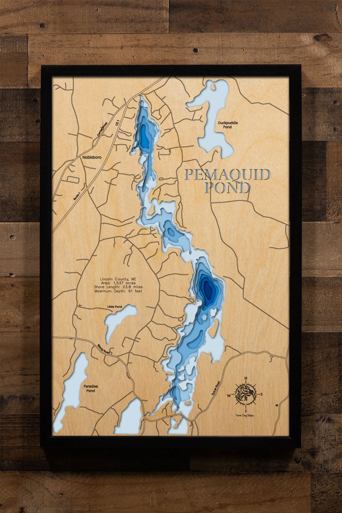 A laser-cut, layered wood map of Pemaquid Pond, Maine, illustrating its winding shoreline, wooded coves, and surrounding landscapes in Lincoln County.