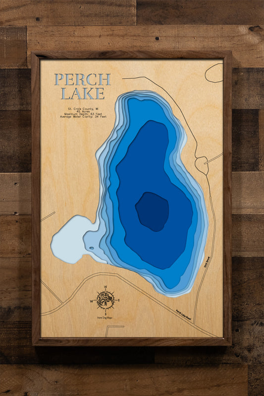 A meticulously detailed, laser-cut, multi-layered wooden map of Perch Lake in St. Croix County, Wisconsin, showcasing the 45-acre glacial kettle lake with Homestead Parklands encompassing two-thirds of its shoreline. The topographic design features natural wood layers highlighting the surrounding oak woodlands and graduated blue water layers illustrating the dramatic depths to 63 feet in this Outstanding Water Resource.