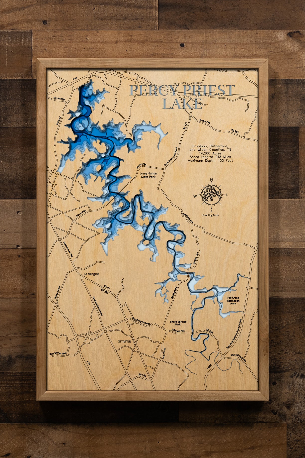 A detailed, laser-cut wooden topographic map of Percy Priest Lake spanning Davidson, Rutherford, and Wilson Counties, Tennessee. The multi-layered design captures the reservoir's 42-mile length and 213 miles of winding shoreline, the dramatic depth variations from shallow upper reaches to the 100-foot maximum near the dam, and the distinctive shape created by the Stones River impoundment with its numerous coves, creek arms, and embayments.