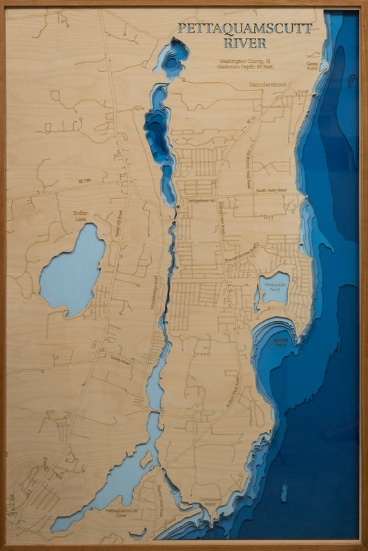 A meticulously detailed, laser-cut, multi-layered wooden map of the Pettaquamscutt River in Washington County, Rhode Island, showcasing the six-mile tidal estuary's winding course through North Kingstown, South Kingstown, and Narragansett. The topographic design features natural wood layers and graduated blue water depths from shallow marshes to the remarkable 65-foot Lower Pond basin.