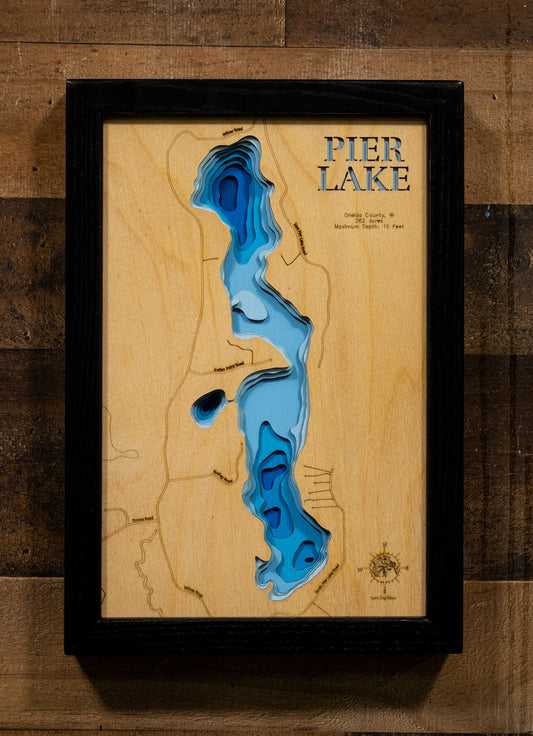 A precision laser-cut, multi-layered wooden map of Pier Lake in Oneida County, Wisconsin, a 262-acre warmwater lake near Minocqua holding Bass, Pike, Walleye, and Panfish. The natural wood top layer captures the lake's natural shoreline in fine detail, while a light-to-dark blue gradient conveys its shallow, productive character. A handcrafted statement piece for any Wisconsin Northwoods cabin, lake home, or outdoor enthusiast's wall.