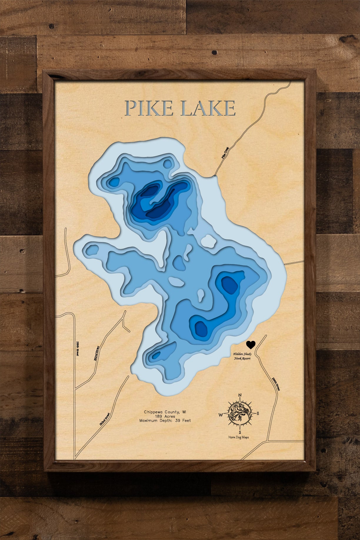 A highly detailed, laser-cut, and multi-layered wooden map of Pike Lake, a natural lake in Chippewa County, Wisconsin. The map shows the lake's distinct shape and its 2.15-mile shoreline. The varying depths of the lake, reaching a maximum of 35 feet, are represented by different layers of wood.