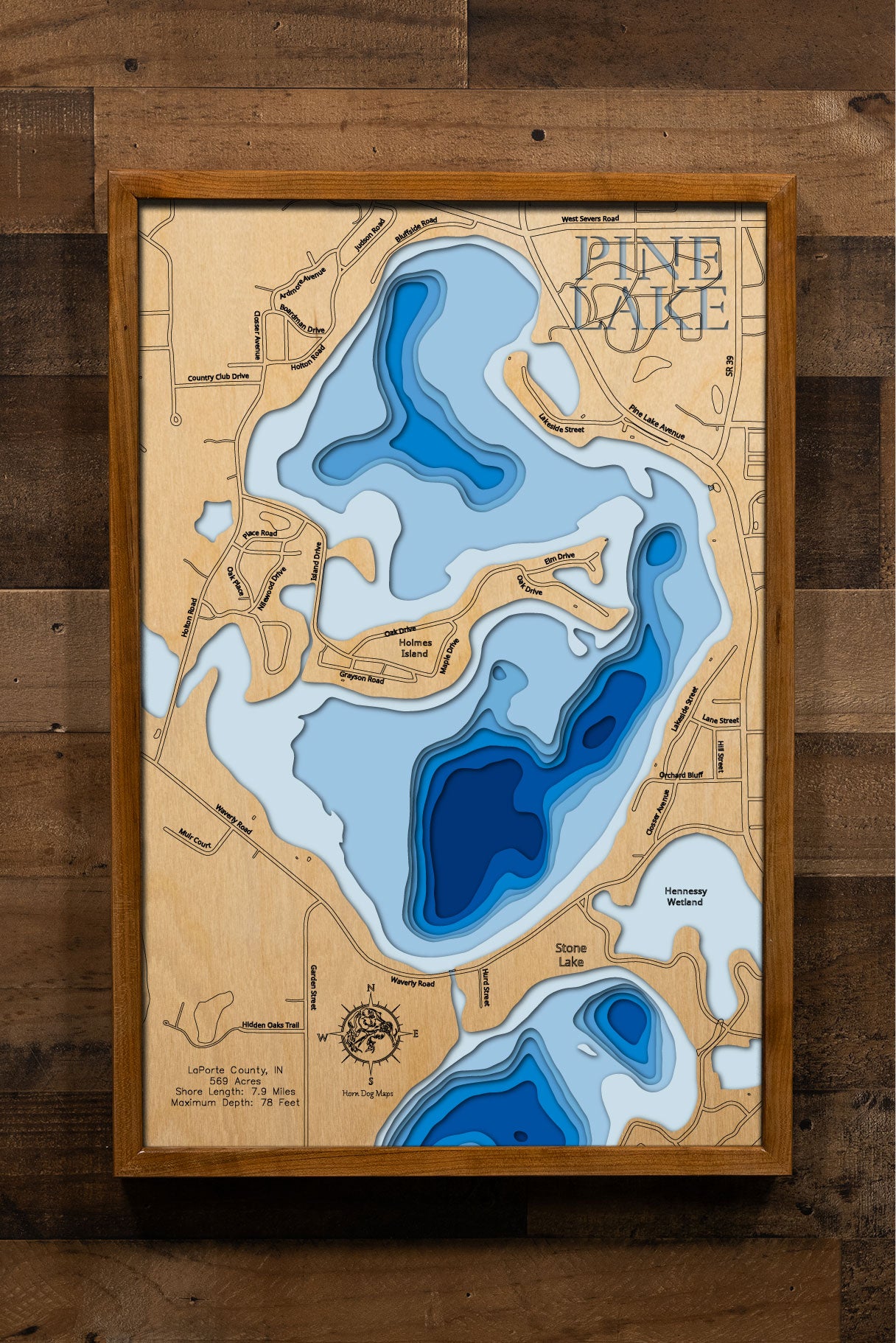 A highly detailed, laser-cut, and multi-layered wooden map of Pine Lake, a natural lake in LaPorte County, Indiana. The map shows the lake's distinct shape and its 7.9-mile shoreline. The varying depths of the lake, reaching a maximum of 78 feet, are represented by different layers of wood.