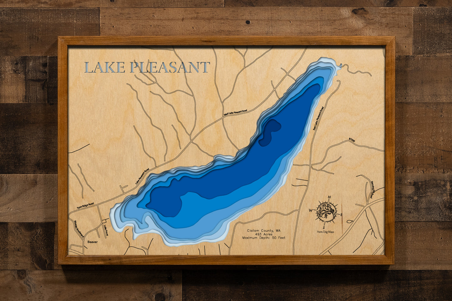 A beautifully detailed, laser-cut wooden topographic map of Lake Pleasant in Clallam County, Washington, showcasing the 493-acre natural basin nestled in the Olympic Peninsula's forested landscape, shoreline access points along U.S. Highway 101, surrounding private timberlands and the lake's position between the Pacific Ocean and Olympic National Park's western wilderness.