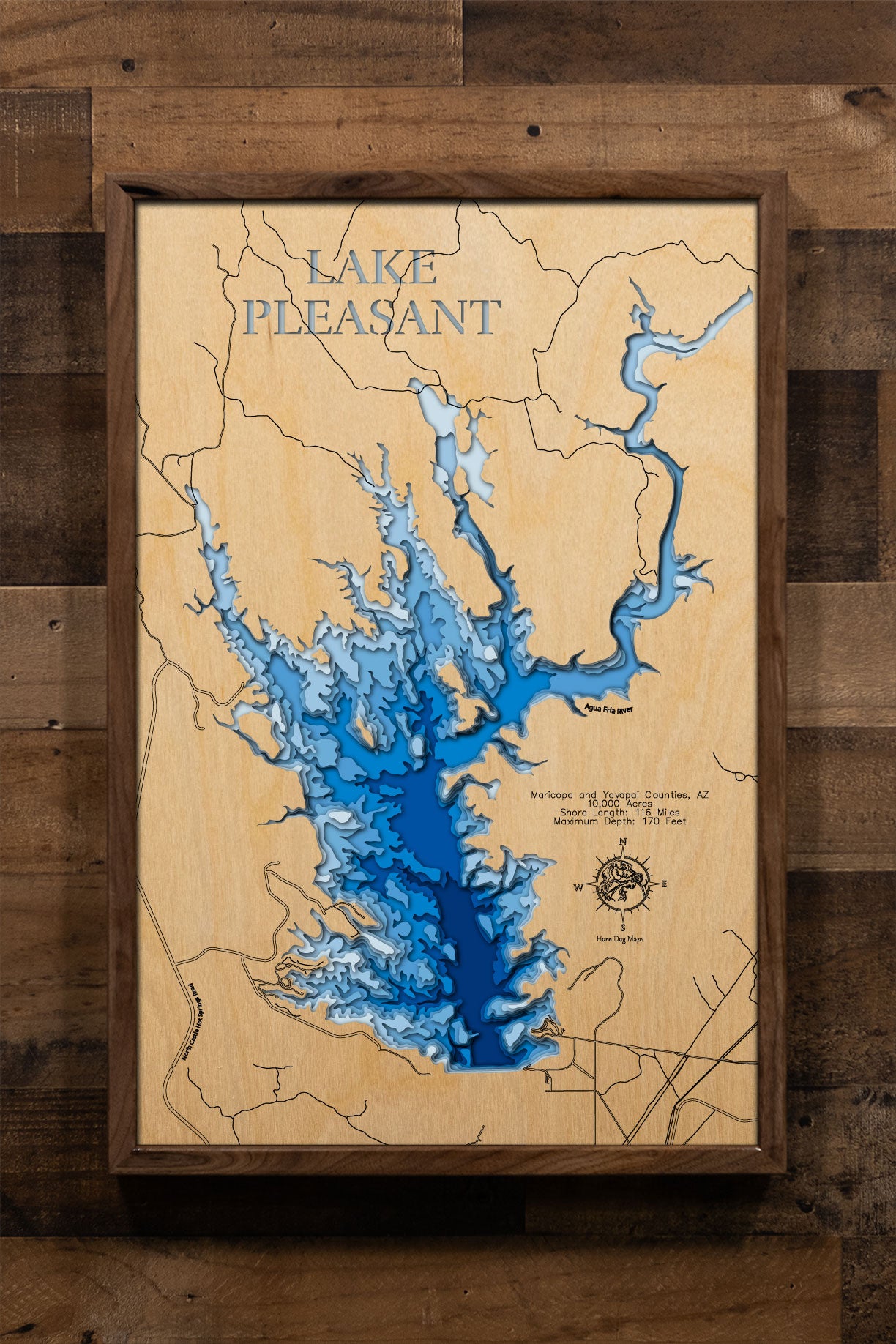A precision laser-cut, multi-layered wooden map of Lake Pleasant in Maricopa and Yavapai Counties, Arizona — a 10,000-acre Sonoran Desert reservoir northwest of Phoenix with 116 miles of dramatic canyon shoreline. The natural wood top layer captures every rugged cove in fine detail, while a light-to-dark blue gradient conveys the lake's 170-foot depth. A handcrafted statement piece for any Arizona lake home, desert retreat, or outdoor enthusiast's wall.