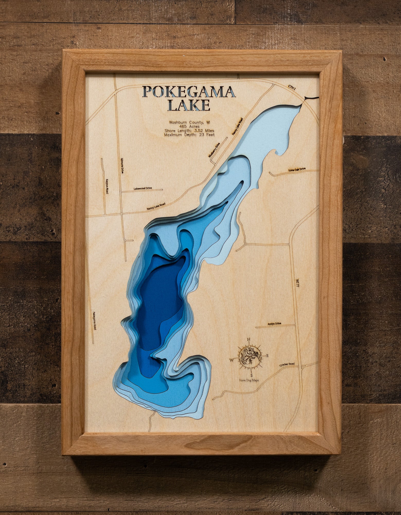 A meticulously crafted laser-cut wooden lake map of Pokegama Lake in Washburn County, Wisconsin. The map features the lake's accurate shape and detailed shoreline, with its impressive depth represented by a deep blue stain. Meticulously etched details include the lake's unique shape, its shore length, and maximum depth, providing both a beautiful piece of art and a detailed, informative guide to this popular Wisconsin lake.