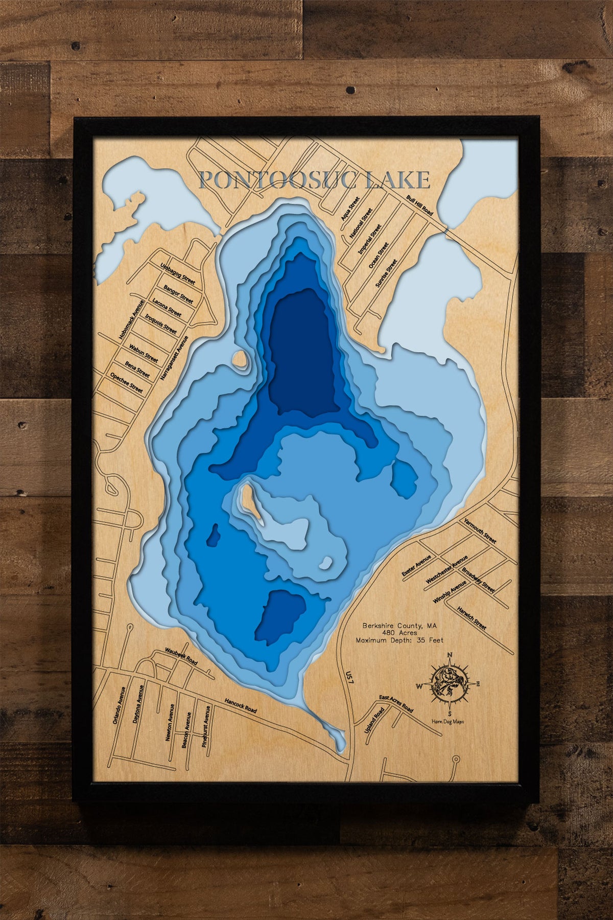 A precision laser-cut, multi-layered wooden map of Pontoosuc Lake in Berkshire County, Massachusetts, a 480-acre great pond straddling Pittsfield and Lanesborough known for its Tiger Muskie fishery and Berkshires setting. The natural wood top layer captures the lake's densely developed shoreline in fine detail, while a light-to-dark blue gradient conveys its 35-foot depth. A handcrafted statement piece for any Massachusetts lake home, Berkshires cottage, or outdoor enthusiast's wall.