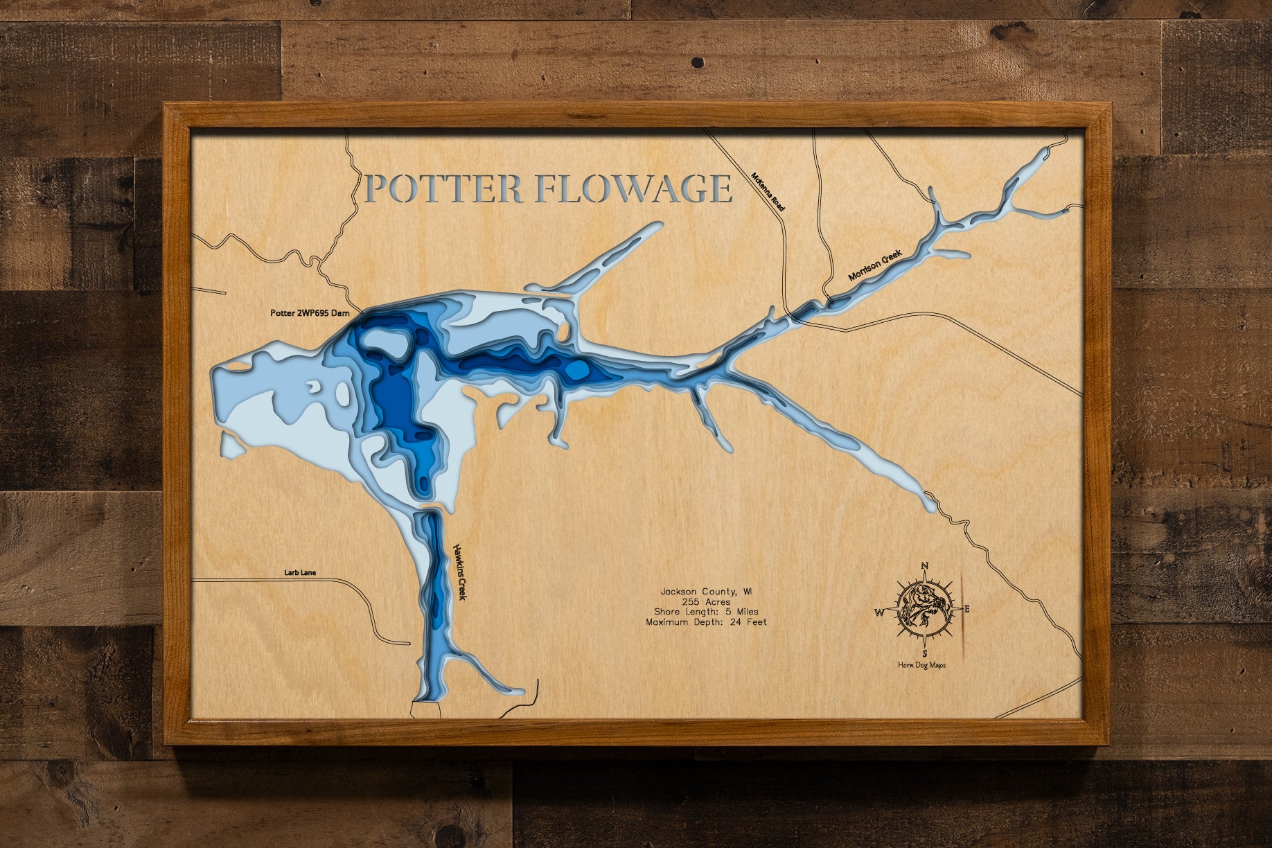 A meticulously detailed, laser-cut, multi-layered wooden topographical map of Potter Flowage in Jackson County, Wisconsin, showcasing the 255-acre impoundment's distinctive T-shape with McKenna and Morrison Creek inlets, numerous bays along approximately five miles of pine-lined shoreline, and extensive lily pad beds. The natural wood top layer frames the dark-water flowage with depth contours from the 7-foot average to the 24-foot maximum near the dam, while graduated blue layers create a gentle visual dep
