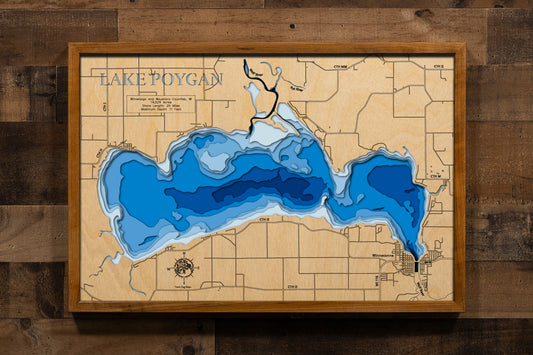 A precision laser-cut, multi-layered wooden map of Lake Poygan spanning Winnebago and Waushara Counties, Wisconsin. The natural wood top layer captures 25 miles of shoreline and the lake's sweeping, shallow basin in fine detail, while a light-to-dark blue gradient highlights the water's depth and dimension. A stunning, rustic statement piece for any Wisconsin lake home, fishing lodge, or sports room.