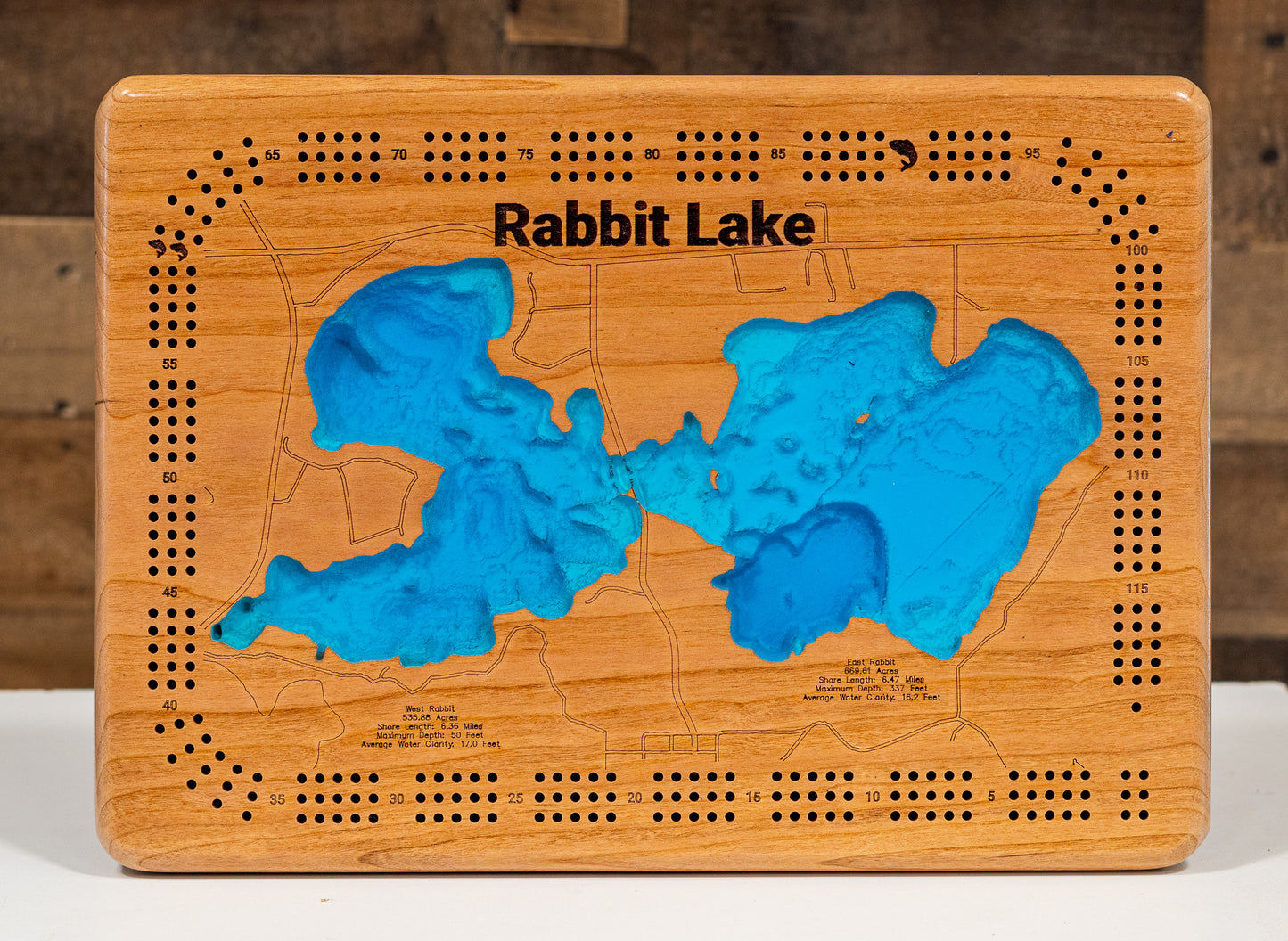 A laser-cut, layered wooden map of Rabbit Lake in Crow Wing County, Minnesota. The distinct shapes of the two interconnected basins and their shared shoreline of 11.81 miles are clearly visible within the forested landscape of central Minnesota. The varying depths of the lake, reaching a remarkable maximum of 337 feet in the eastern basin, are represented by different layers of wood, illustrating its impressive and dramatic underwater topography.
