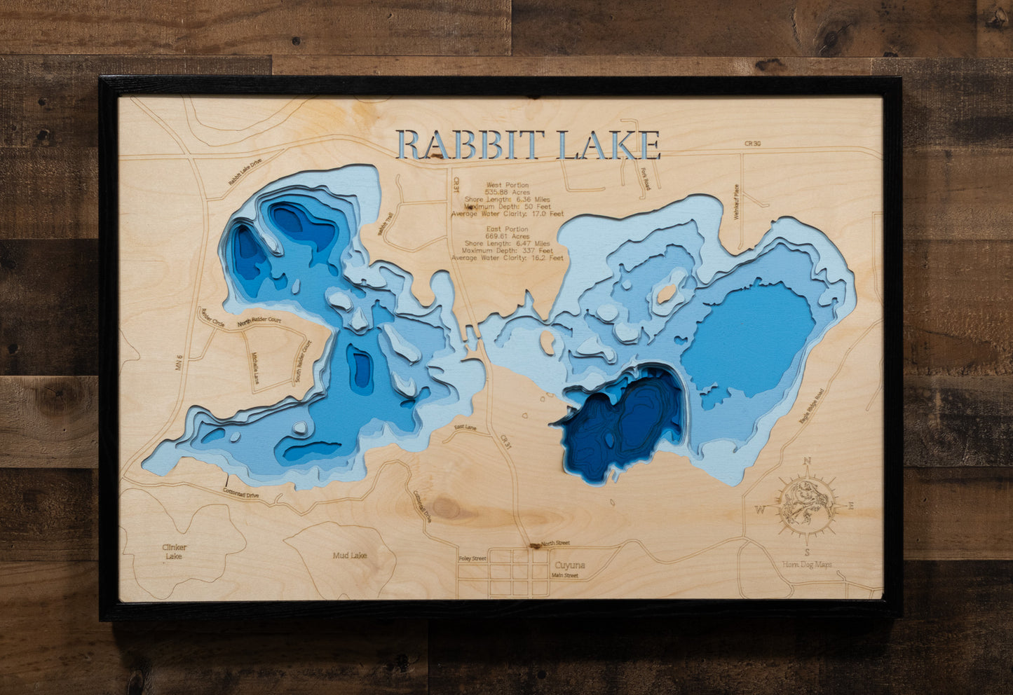A laser-cut, layered wooden map of Rabbit Lake in Crow Wing County, Minnesota. The distinct shapes of the two interconnected basins and their shared shoreline of 11.81 miles are clearly visible within the forested landscape of central Minnesota. The varying depths of the lake, reaching a remarkable maximum of 337 feet in the eastern basin, are represented by different layers of wood, illustrating its impressive and dramatic underwater topography.