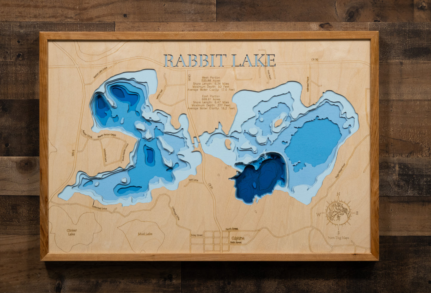 A laser-cut, layered wooden map of Rabbit Lake in Crow Wing County, Minnesota. The distinct shapes of the two interconnected basins and their shared shoreline of 11.81 miles are clearly visible within the forested landscape of central Minnesota. The varying depths of the lake, reaching a remarkable maximum of 337 feet in the eastern basin, are represented by different layers of wood, illustrating its impressive and dramatic underwater topography.
