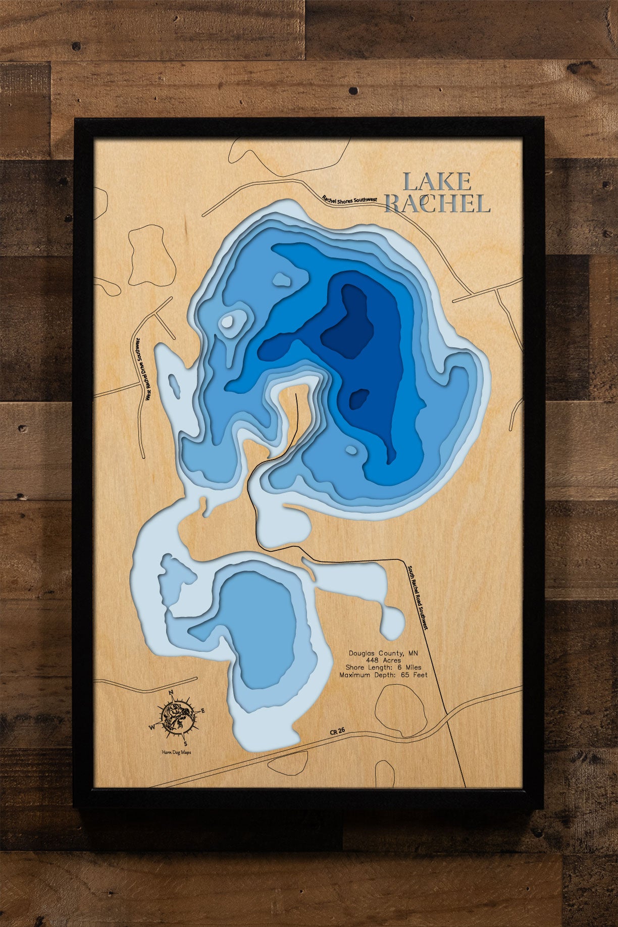 A precision laser-cut, multi-layered wooden map of Lake Rachel in Douglas County, Minnesota, a 448-acre clear water lake near Lowry and Kensington with 6 miles of tree-lined shoreline and a 65-foot maximum depth. The natural wood top layer captures every curve of this ecologically rich lake in fine detail, while a light-to-dark blue gradient conveys its impressive depth. A handcrafted statement piece for any Minnesota lake home, cabin, or outdoor enthusiast's wall.