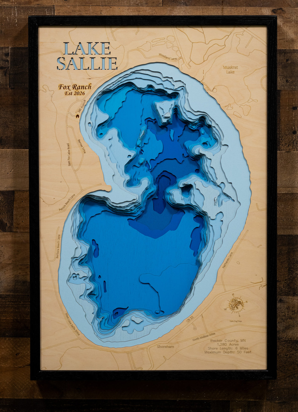 A precision laser-cut, multi-layered wooden map of Lake Sallie in Becker County, Minnesota, a 1,280-acre lake near Detroit Lakes holding one of the most diverse fisheries in west-central Minnesota. The natural wood top layer captures 6 miles of shoreline in fine detail, while a light-to-dark blue gradient conveys the lake's 50-foot depth. A handcrafted statement piece for any Minnesota lake home, cabin, or outdoor enthusiast's wall.