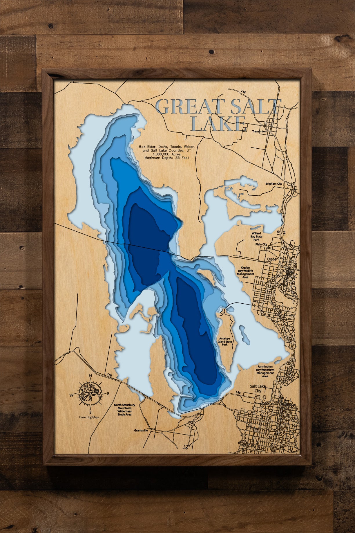An intricately detailed, multi-layered laser-cut wooden topographic map of Great Salt Lake spanning five Utah counties, showcasing the lake's massive 1,088,000-acre expanse with its remarkably shallow 35-foot maximum depth, the eleven islands including prominent Antelope Island, the railroad causeway dividing the northern and southern sections, and the dramatic shoreline variations that reflect this terminal lake's prehistoric origins as part of ancient Lake Bonneville.