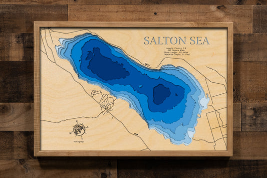 A laser-cut, layered wood map of the Salton Sea, California, highlighting its shoreline and surrounding desert landscape.