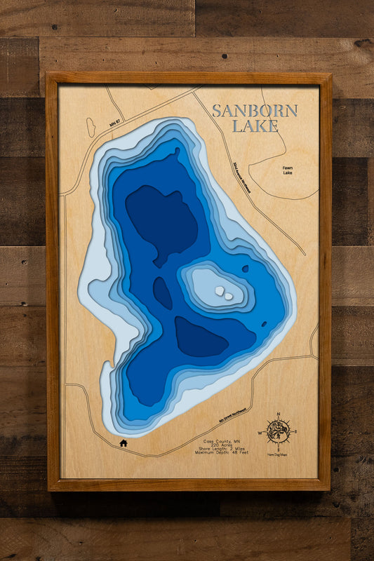 A precision laser-cut, multi-layered wooden map of Sanborn Lake in Cass County, Minnesota, a clear water lake east of Backus near Hackensack in the heart of Paul Bunyan Country. The natural wood top layer captures 2 miles of shoreline in fine detail, while a light-to-dark blue gradient conveys the lake's 48-foot depth. A handcrafted statement piece for any Minnesota lake cabin, home, or outdoor enthusiast's wall.