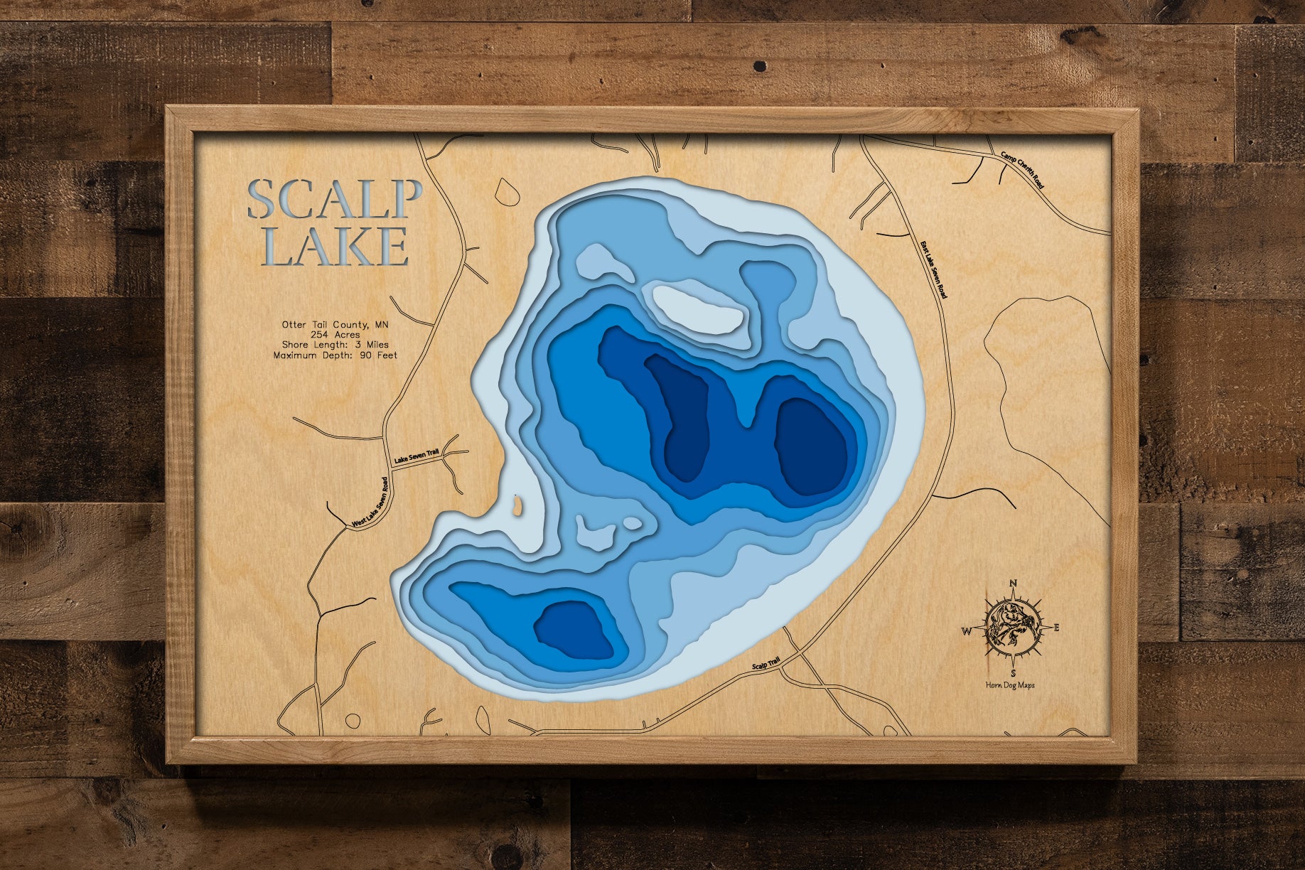 A meticulously detailed, laser-cut, multi-layered wooden topographical map of Scalp Lake in Otter Tail County, Minnesota, showcasing the 254-acre lake's surface with dramatic depth contours illustrating the transition from shallower areas to the impressive 90-foot maximum depth. The natural wood top layer frames three miles of shoreline with the public boat launch, while graduated blue layers create a striking visual depth gradient.