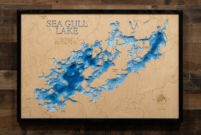 A highly detailed, laser-cut, and multi-layered wooden map of Sea Gull Lake, a natural lake in Cook County, Minnesota. The map shows the lake's distinct shape and its extensive 74.97-mile shoreline. The varying depths of the lake, reaching a remarkable 145 feet, are represented by different layers of wood.