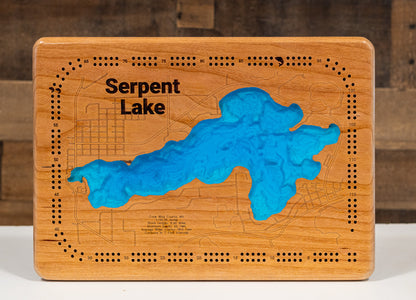 A laser-cut, layered wooden map of Serpent Lake in Crow Wing County, Minnesota. The distinct shape of this natural lake, with its 8.93-mile shoreline, is clearly visible within the forested landscape of central Minnesota near the towns of Crosby and Deerwood. The varying depths of the lake, reaching a maximum of 65 feet, are represented by different layers of wood, illustrating its impressive underwater topography.