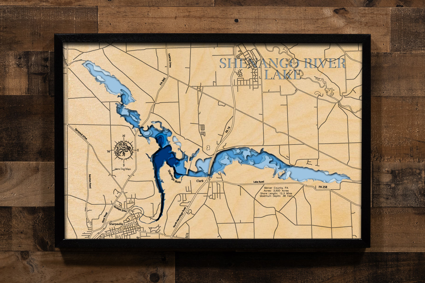 A highly detailed, 3D laser-cut wooden map of Shenango River Lake in Mercer County, Pennsylvania. The multi-layered design uses different wood tones to illustrate the lake's bathymetric contours and deepest points. Etched details include the lake name, county lines, shoreline roads, and the surrounding state park, creating a unique and intricate piece of art.