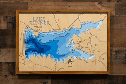 A precision laser-cut, multi-layered wooden map of Lake Skinner in Riverside County, California, a 1,400-acre reservoir near Temecula in the heart of Temecula Valley Wine Country managed for fishing and drinking water supply. The natural wood top layer captures the lake's rolling, hill-rimmed shoreline in fine detail, while a light-to-dark blue gradient brings its calm, clear character to life. A handcrafted statement piece for any Southern California lake home, Temecula retreat, or outdoor enthusiast's wal