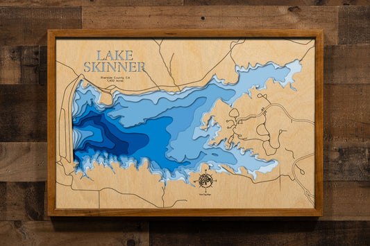 A precision laser-cut, multi-layered wooden map of Lake Skinner in Riverside County, California, a 1,400-acre reservoir near Temecula in the heart of Temecula Valley Wine Country managed for fishing and drinking water supply. The natural wood top layer captures the lake's rolling, hill-rimmed shoreline in fine detail, while a light-to-dark blue gradient brings its calm, clear character to life. A handcrafted statement piece for any Southern California lake home, Temecula retreat, or outdoor enthusiast's wal