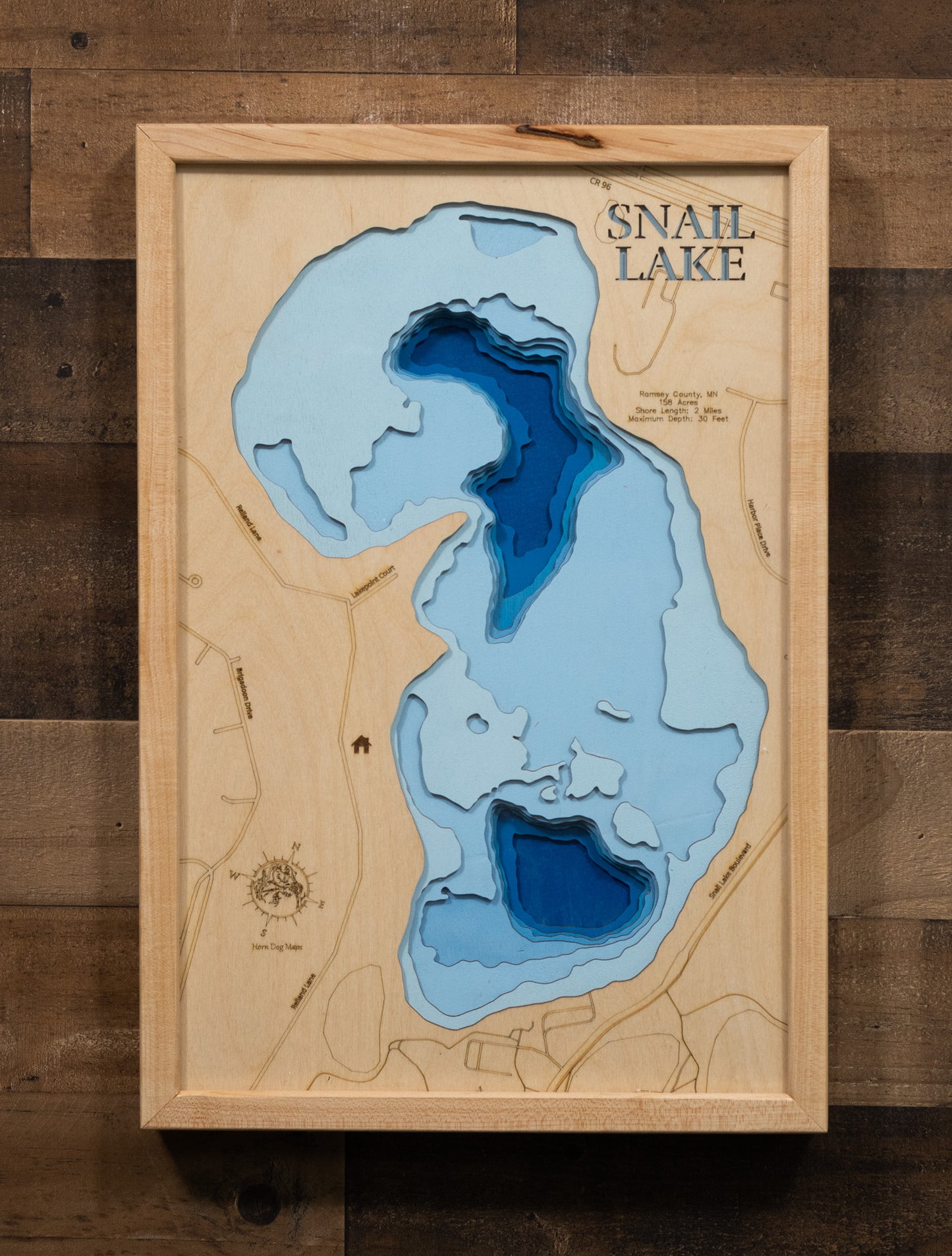 A detailed laser-cut wooden map of Snail Lake in Ramsey County, Minnesota, capturing the intimate 158-acre lake in Shoreview with its 2 miles of shoreline, 35-acre wetland on the northwest side, depth contours showing the 30-foot maximum depth, and the Snail Lake Regional Park location with beach and boat access on the southern shore.