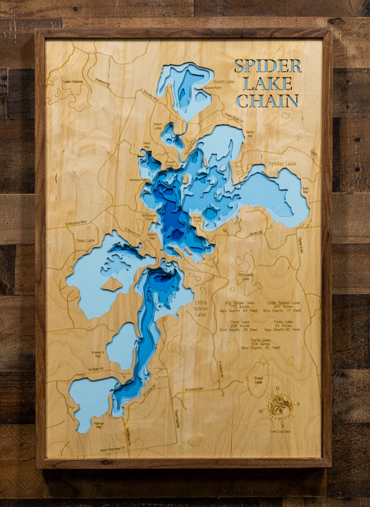 A 3D wooden depth map of Spider Lake Chain, featuring layered blue and light blue wood sections representing water depth, mounted on a rustic dark wood plank wall.