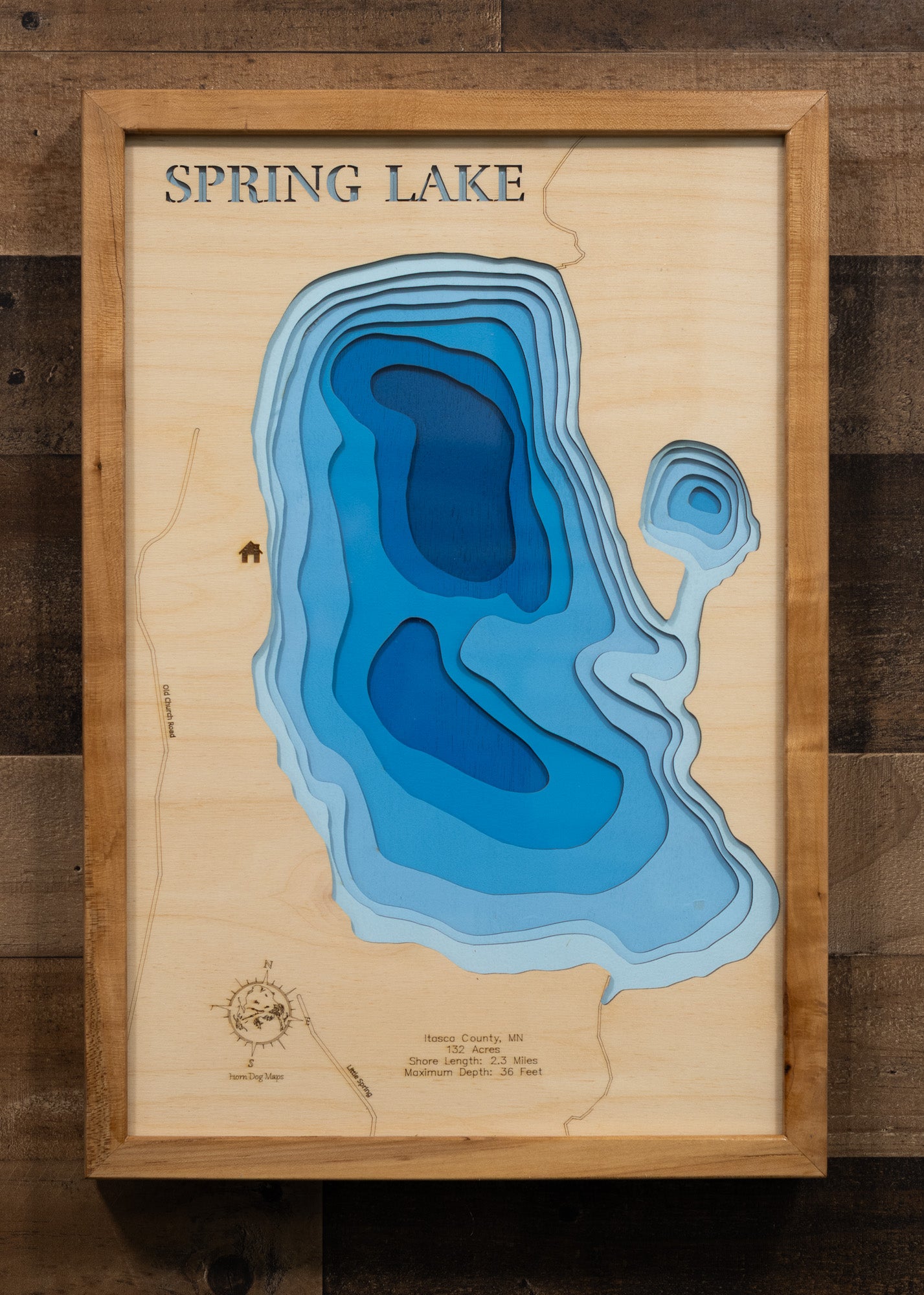 A laser-cut, layered wood map of Spring Lake, Itasca County, Minnesota, illustrating its shoreline and surrounding forested landscape.