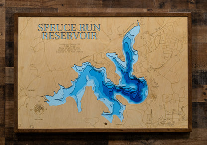 A laser-cut, layered wooden map of Spruce Run Reservoir in Hunterdon County, New Jersey. The distinct shape of this large reservoir, with its 15-mile shoreline, is clearly visible within the central New Jersey landscape. The varying depths of the lake, now confirmed to reach a maximum of 72 feet and detailed by 12-foot contour intervals, are represented by different layers of wood, illustrating its impressive underwater topography.