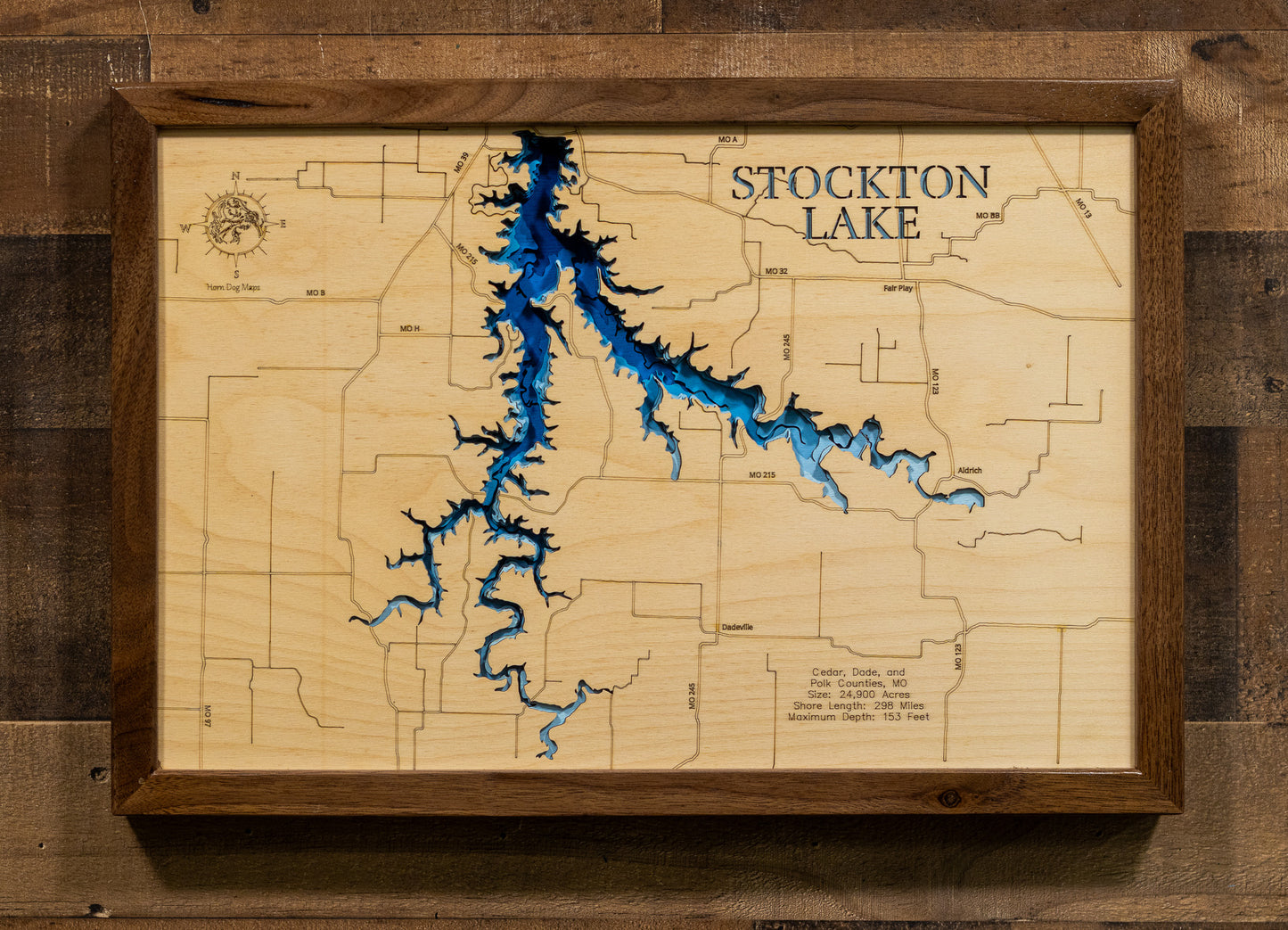 A laser-cut, layered wooden map of Stockton Lake, located in Cedar, Dade, and Polk Counties, Missouri. The intricate and extensive shoreline of the reservoir is clearly depicted, showcasing its significant size within southwest Missouri. The varying depths of the lake, reaching a maximum of 153 feet, are represented by different layers of wood, creating a three-dimensional effect of this prominent Missouri water body.