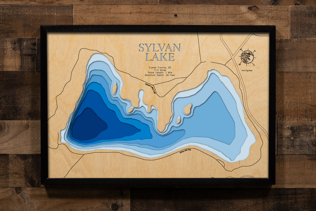 A precision laser-cut, multi-layered wooden map of Sylvan Lake in Custer County, South Dakota, the Crown Jewel of Custer State Park, a 17-acre granite-rimmed reservoir at 6,145 feet in the Black Hills with 1 mile of dramatic shoreline. The natural wood top layer captures every rock formation and cove in fine detail, while a light-to-dark blue gradient conveys its 30-foot depth. A handcrafted statement piece for any Black Hills home, South Dakota cabin, or outdoor enthusiast's wall.