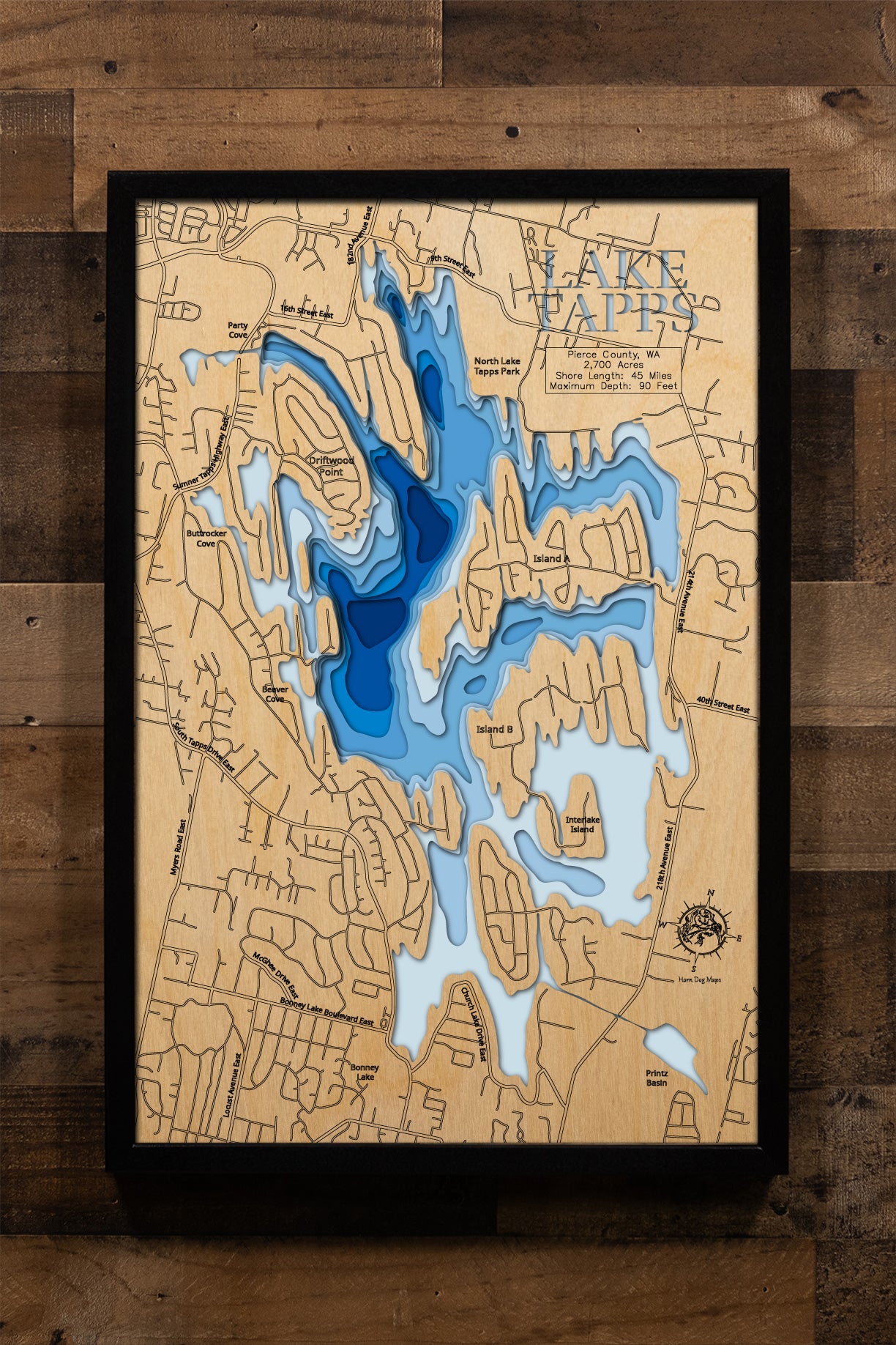 A meticulously crafted, multi-layered wooden topographic map of Lake Tapps in Pierce County, Washington, featuring laser-cut depth contours revealing the reservoir's 90-foot maximum depth, the intricate 45-mile shoreline with its distinctive islands and peninsulas, location markers for North Lake Tapps Park and Allan Yorke Park boat launches, and Mount Rainier's profile visible to the south.