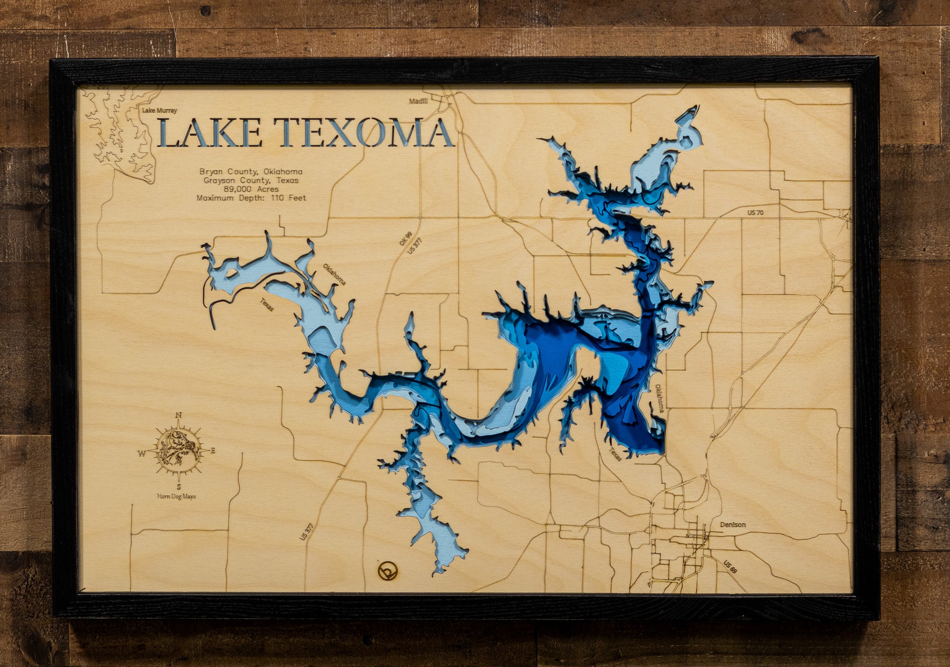 An intricately detailed, laser-cut, multi-layered wooden map of Lake Texoma spanning the Oklahoma-Texas border. The map showcases the reservoir's massive 89,000-acre expanse, depth contours revealing the 100-foot maximum depth near Denison Dam, the distinctive 580 miles of serpentine shoreline, and the confluence of the Red and Washita Rivers.