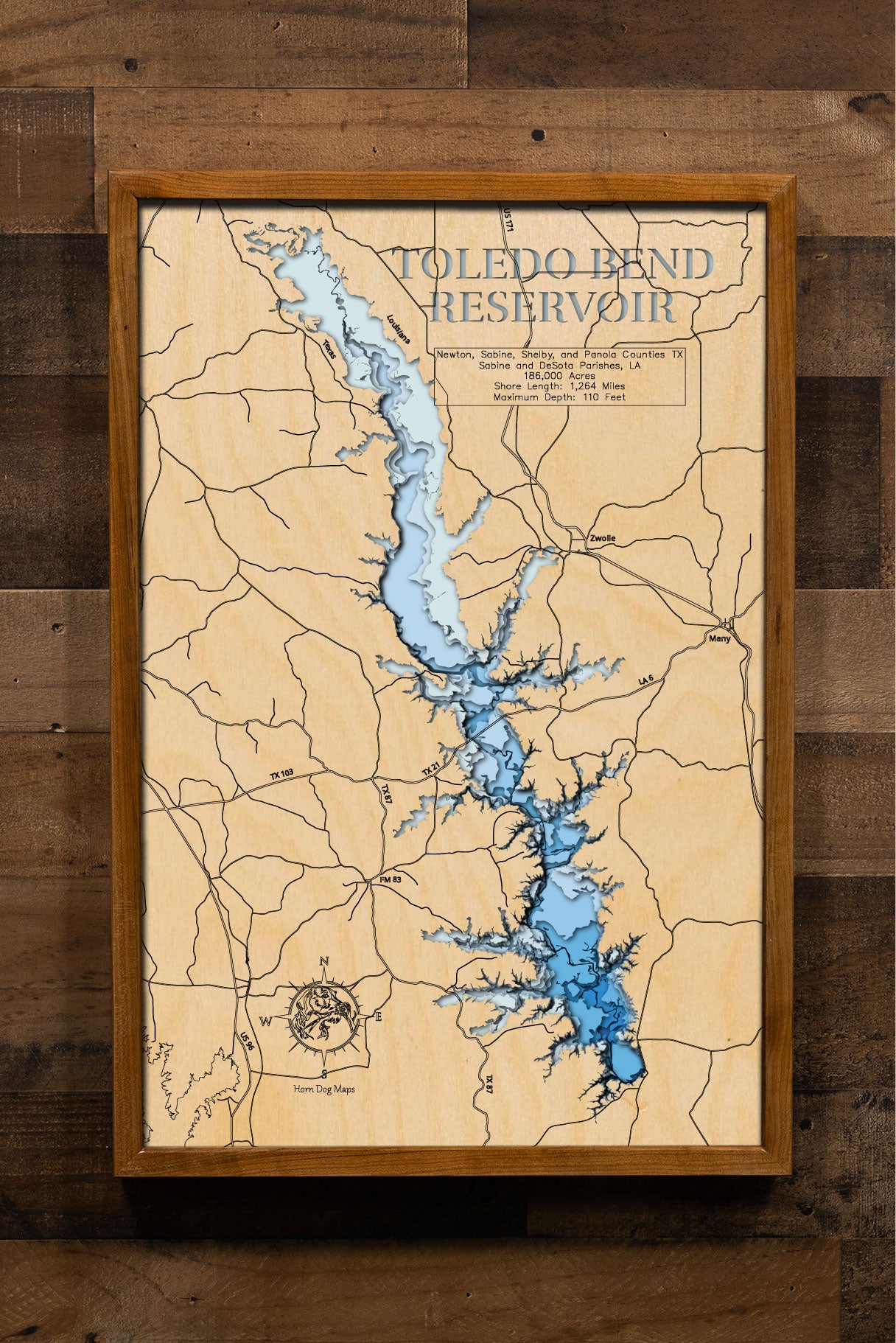 A laser-cut, layered wooden map of Toledo Bend Reservoir, located on the border of Louisiana and Texas. The expansive and intricate shape of this massive reservoir, stretching along the Sabine River, is clearly visible within the landscape of both states. The varying depths of the lake, reaching a maximum of 110 feet, are represented by different layers of wood, illustrating its underwater topography.
