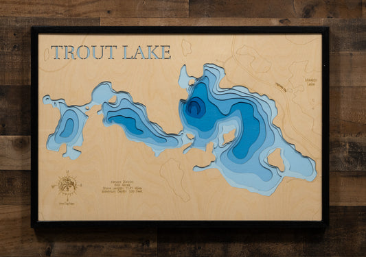 A laser-cut, layered wooden map of Trout Lake in Kenora District, Ontario, Canada. The distinct shape of this 600.43-acre lake, with its 11.21-mile shoreline, is visible within the northwestern Ontario landscape, indicating its position relative to nearby Laclu and other lakes in the area.